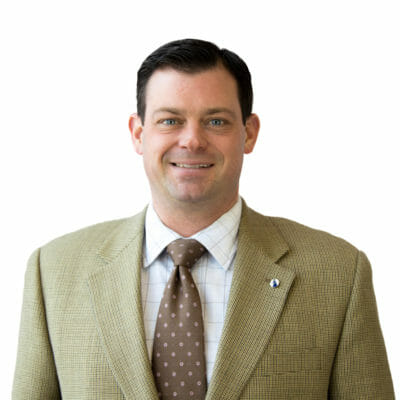Brandon Farmer at bank of the james wearing a tweed suit jacket with a white shirt and brown tie and a bank of the james lapel pin