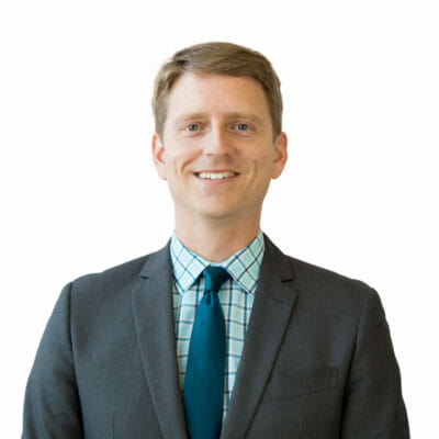 Brian Cash at Bank of the James wearing a grey suit jacket, teal and blue button down shirt and a teal tie