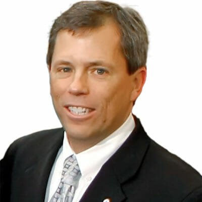 Michael Syrek from Bank of the James wearing a black suit jacket, white button down shirt and grey tie with a bank of the james lapel pin